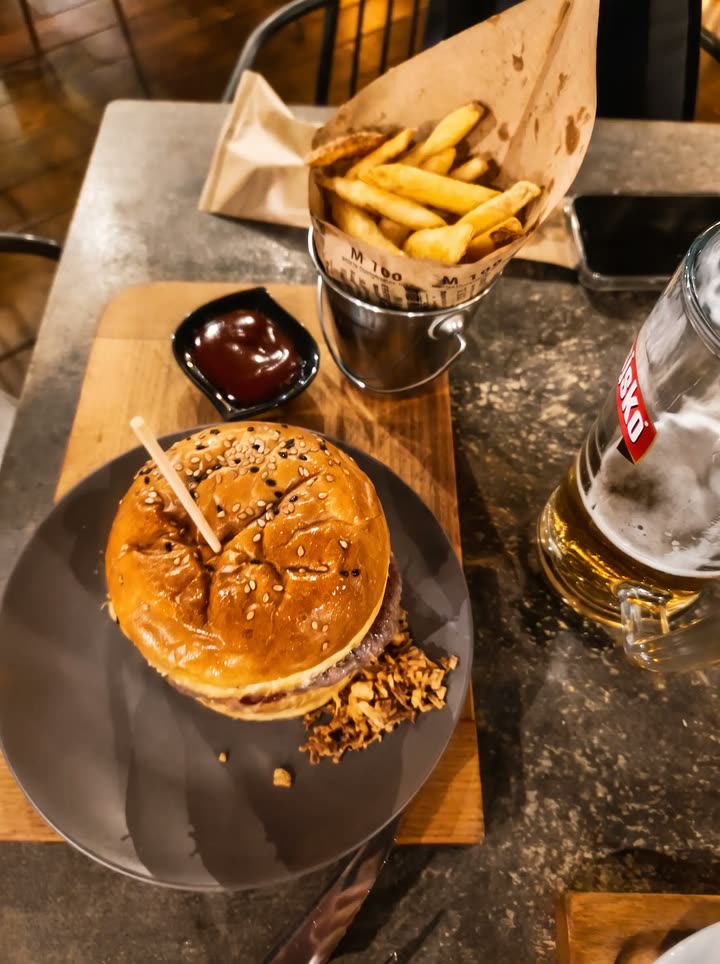 Burger s hrskavim lukom, krumpirići u papirnatom tuljcu i krigla Ožujskog