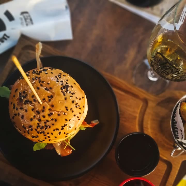 Burger Tartuf odozgo — pogačica sa sezamom na crnom tanjuru